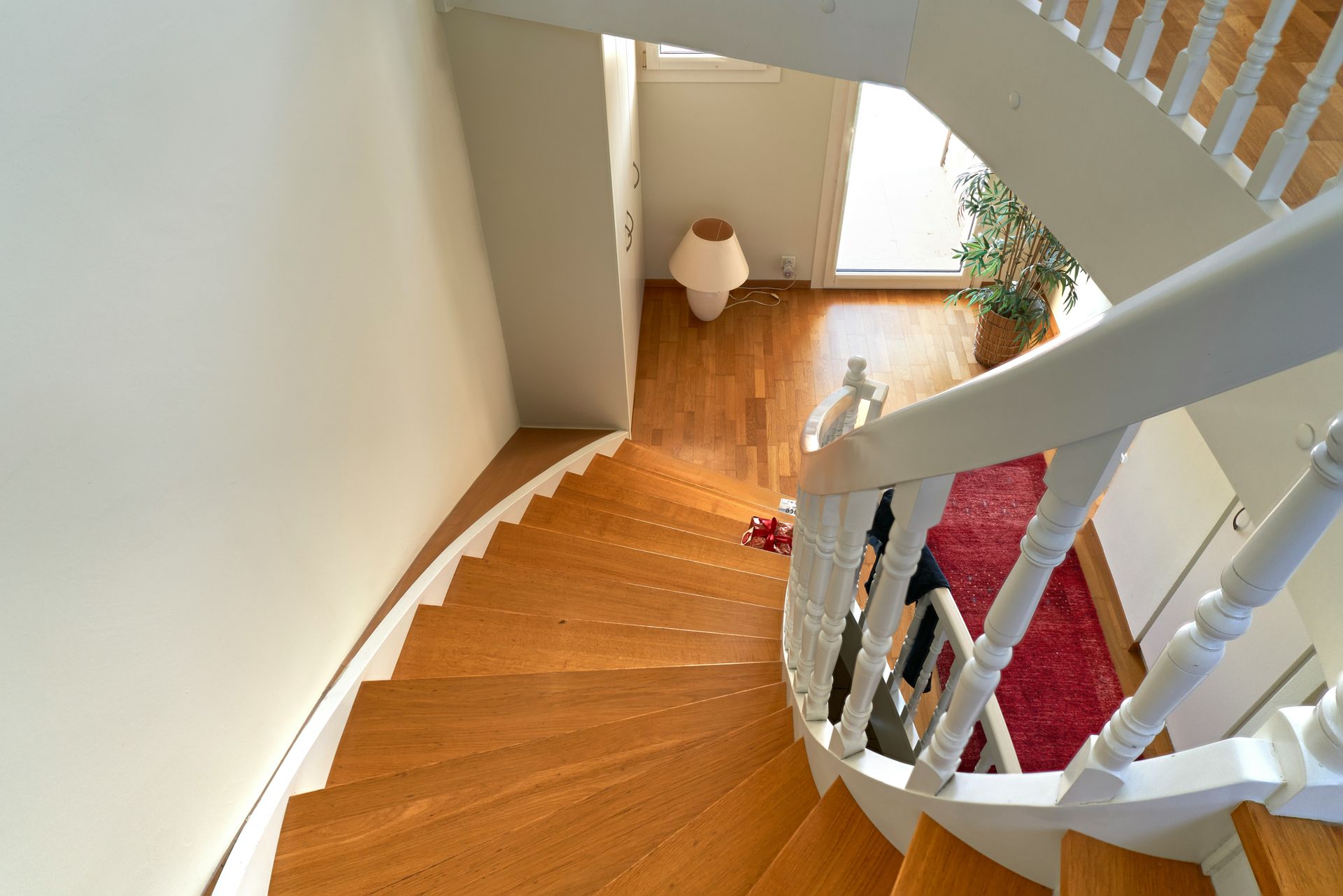 Wooden staircase with white railing and red rug