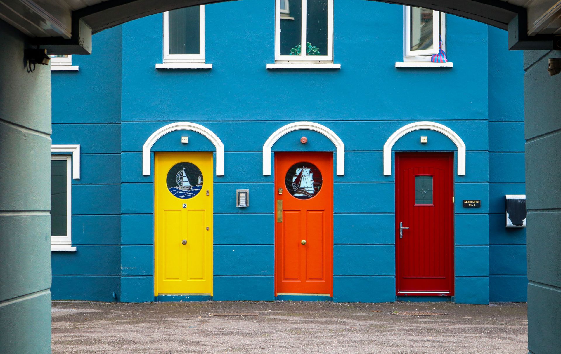 Vibrant blue building with yellow, orange, and red doors in Cobh, Ireland.